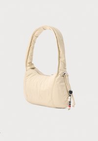 Beež värvi ümarate servadega õlakott, valmistatud pehmest tekstuuriga materjalist, millel on lukuga sulgemine ja dekoratiivne rihmaga detail.