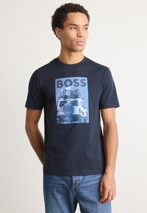 T-shirt in cotone blu navy con maniche corte, caratterizzato da una stampa grafica di un veicolo e dalla parola "BOSS" in lettere grassetto.