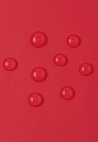 Rote Oberfläche mit unterschiedlich großen, glänzenden, kreisförmigen roten Tropfen, die Licht reflektieren und über das Material verstreut sind.