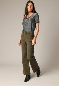 Grijze metallic korte mouwen top gecombineerd met olijfgroene wijde broek en zwarte enkellaarsjes met hak. Soepele stof, ontspannen pasvorm en zakken.