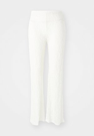 Valged pitsilised laihed püksid, millel on tekstuuriga muster, elastne vöökoht ja veidi läbipaistev viimistlus. Õmmeldud kitsas vormis.