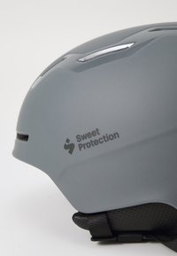 Gray helmet with a matte finish, ventilation slots, and black textured accents. Features "Sweet Protection" branding on the side.