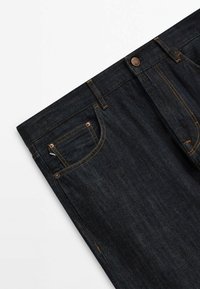 Tummansiniset farkut suoraan leikkauksella, joissa on kultaiset tikkaukset, viisi taskua ja nappikiinnitys. Sileä pinta, vähäisiä kulumia.