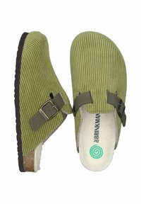 Green corduroy clogs with a textured surface, buckled strap detail, and beige lining. Features a brown rubber sole and a minimalist logo.