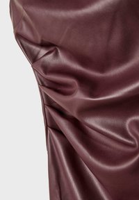 Burgundy konstläder med slät yta och framträdande veck som lyfter fram dess design och lyxiga utseende.