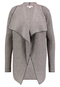 Svetr s vzorem houndstooth v jemném šedém a krémovém odstínu. Má otevřenou přední část, dlouhé rukávy a volný límec, s kontrastním lemem.