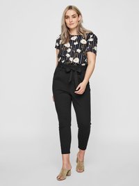 Black high-waisted pants with a belted waist paired with a floral patterned navy blouse. Model wearing beige open-toe heels.
