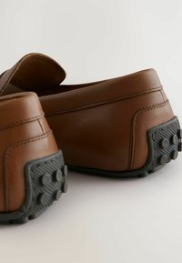 Brune læder slip-on sko med en tekstureret overdel, gummisåler med runde greb og synlige syninger.