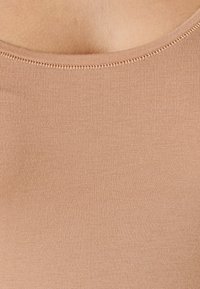 Canottiera beige a costine con scollatura rotonda e cuciture in vista. Tessuto morbido e design aderente per un comfort ottimale.
