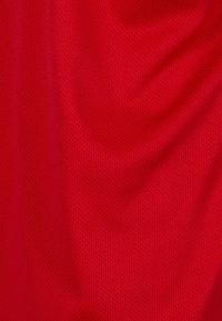 Țesătură din plasă roșie, ușoară, respirabilă, cu o suprafață texturată ce prezintă găuri mici și uniforme pentru ventilație.