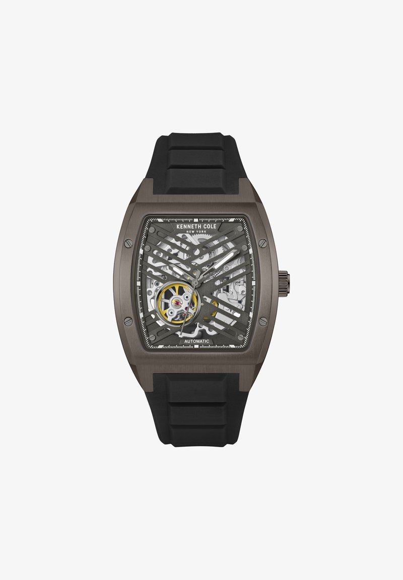 Kenneth Cole automatisk klocka har en transparent skeleton urtavla, svart silikonarmband och ett rektangulärt grått hölje med nätdetaljer.