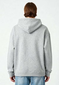 La felpa grigia presenta un grande cappuccio, polsini e orlo a costine. Texture morbida con una vestibilità rilassata, mostrata da dietro su uno sfondo chiaro.