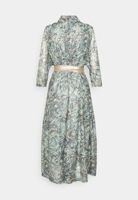 Lång blommig klänning i ljusgrön med ett bladmönster, med krage, trekvartslånga ärmar och ett metalliskt guld bälte.