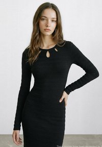 Schwarzes langärmeliges Kleid mit gerippter Textur, rundem Ausschnitt mit drei Schlüsselloch-Aussparungen, figurbetonter Silhouette und weichem Stoff.