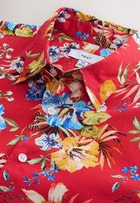 Rood overhemd met knopen en een kleurrijk tropisch bloemenpatroon, met blauwe, gele en witte bloemen en groene bladeren, maat medium.