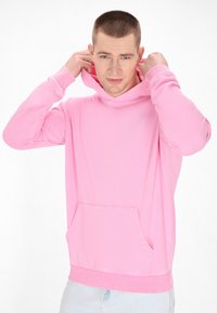 Felpa rosa con cappuccio, dotata di tasca frontale, polsini e orlo a coste. Il tessuto sembra morbido e ha una texture liscia, progettata per un abbigliamento casual.