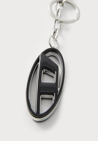 Portachiavi con un design ovale nero e argento, con una lettera "A" prominente in stile 3D rialzato. Realizzato in metallo con una finitura liscia.