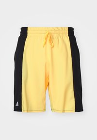 Żółte i czarne spodenki sportowe z elastycznym pasem, sznurkiem, bocznymi kieszeniami oraz logo Adidas na lewej nodze.