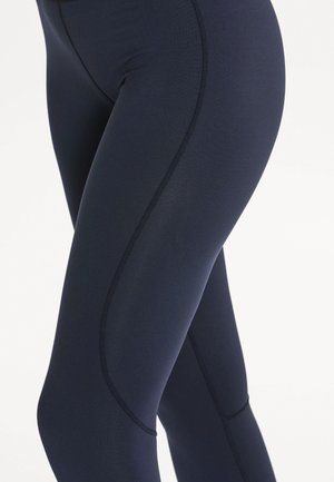 Mørkeblå leggings lavet af strækbart materiale, med en glat tekstur, tætsiddende design og kontrasterende syninger for ekstra detalje.