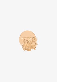 Losse poederfoundation in een lichte beige tint, gedeeltelijk geplet, met een gladde, matte textuur en fijne korrels.