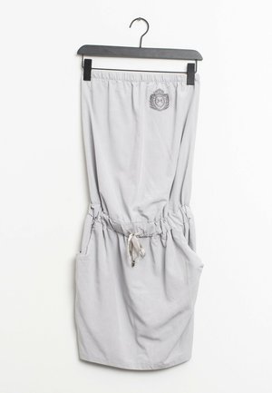Lysegrå nederdel med elastisk taljebånd og snøre, to sidelommer, dekorativt emblem ved taljebåndet, glat stofstruktur.