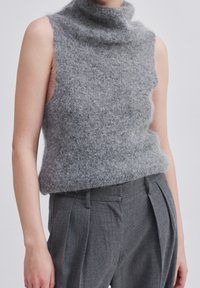 Grå ärmlös polokrage-tröja gjord av luddig, texturerad fleece, kombinerad med grå veckade byxor.