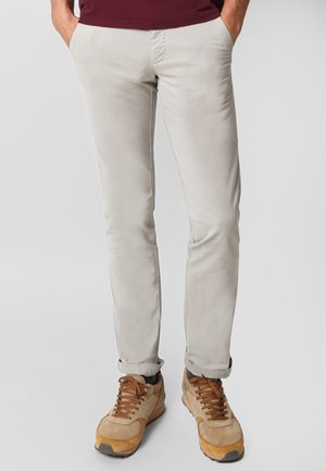 Lichtgrijze slim-fit broek met een gladde textuur, vijf zakken en opgerolde manchetten, gecombineerd met tan, gestructureerde sneakers.