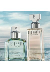 Två Calvin Klein Eternity doftflaskor: en kvadratisk, klar glasflaska med ett silverlock för män; en rektangulär, frostad glasflaska för kvinnor.