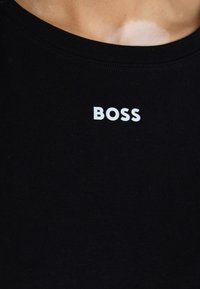 Črna bombažna majica s krožno izrezom. Ima izrazit bel napis "BOSS" natisnjen spredaj. Mehka tekstura, prilegajoč kroj.