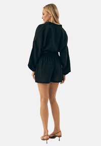 Czarny zestaw składający się z lnianej koszuli i szortów, o luźnym kroju, z długimi rękawami, elastycznym paskiem w talii, zestawiony z sandałami na paski.