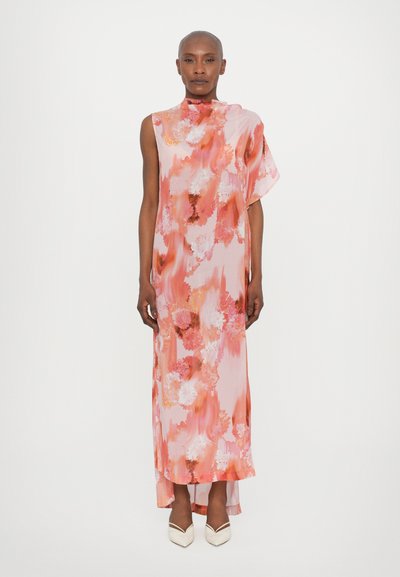 Langes, ärmelloses rosa Kleid mit floralen Mustern in Pfirsich- und Weißtönen; glattes, leichtes Material; asymmetrischer Saum; kombiniert mit weißen High Heels.