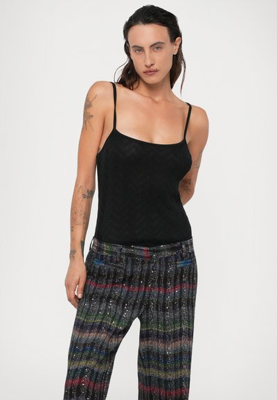 Top nero senza maniche con motivo a zigzag; abbinato a pantaloni a righe multicolore e testurizzati con accenti di paillettes e tasche.