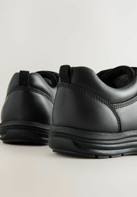 Chaussures en cuir noir avec des dessus texturés, des cols rembourrés et des semelles en caoutchouc. Présente des languettes de tirage au talon et des coutures contrastées.