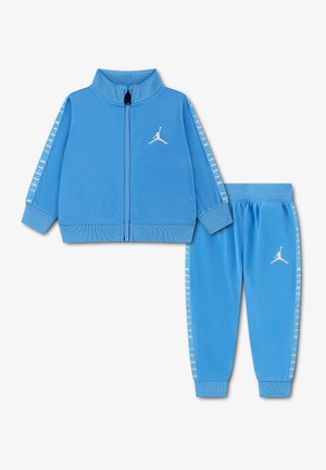 Survêtement bleu pour enfants avec veste zippée et pantalon de jogging, tous deux ornés de logos Jordan blancs et de texte du logo le long des manches et des jambes.
