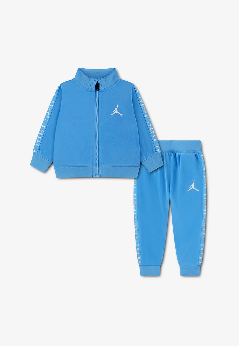 Survêtement bleu pour enfants avec veste zippée et pantalon de jogging, tous deux ornés de logos Jordan blancs et de texte du logo le long des manches et des jambes.
