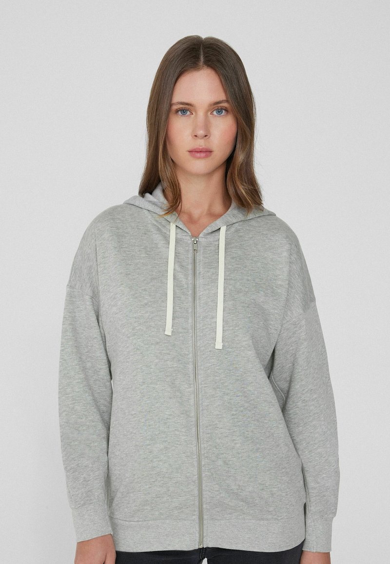 Grauer Reißverschluss-Hoodie aus weichem Stoff mit Kapuze. Verfügt über leichte Kordeln und gerippten Saum. Lockere Passform und lange Ärmel.