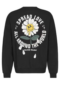 Felpa nera con una grande grafica di un fiore sorridente con accenti gialli che colano. Il testo dice: "Diffondi amore in tutto il mondo."