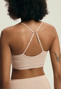 Jasnoróżowy ribbed braletka z regulowanymi ramiączkami. Posiada plecy w stylu racerback i bezszwowe wykończenie. Miękka tkanina i minimalistyczny styl.