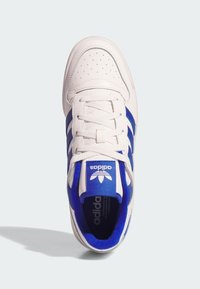 White leather sneaker with blue accents, featuring three stripes, a perforated toe cap, and a cushioned tongue. Clear logo on the tongue.