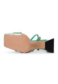 Sanda moderna de tiras verdes con punta cuadrada, base nude y tacón bloque negro texturizado. Las tiras tienen un acabado suave y un detalle mínimo.