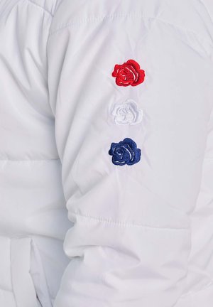 Manica di giacca imbottita bianca con tre rose ricamate: rossa, bianca e blu, disposte verticalmente, con una texture liscia e polsino elastico.