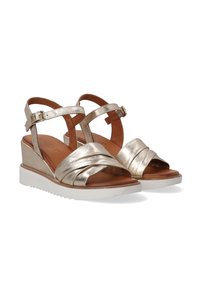 Gouden metallic wedge sandalen met kruislings aangebrachte bandjes aan de voorkant, verstelbaar enkelbandje en een witte rubberen zool. Gladde textuur en een elegante vormgeving.