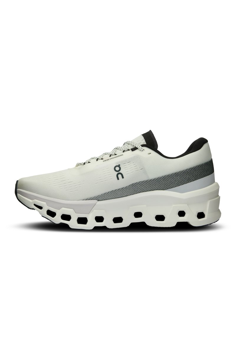 Witte sportieve schoen met grijze accenten, een ademende mesh bovenkant, een gevoerde zool en hexagonale uitsparingen in de buitenzool voor verbeterde grip.