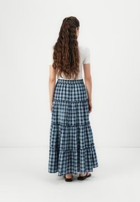 Maxiskjørt i blårutete design med volanger. Elastisk linning og ankel-lengde. Laget av lettvektig stoff. Ingen synlig hardvare.