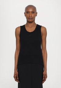 Schwarzes, ärmelloses Tanktop aus glattem Stoff. Verfügt über gewellte Kanten entlang des Ausschnitts und ein dezentes, besticktes Logo auf der Brust.