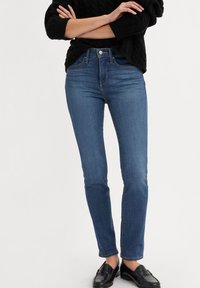 Jeans in denim blu a vita alta con vestibilità dritta, caratterizzati da un classico design a cinque tasche e dettagli di cucitura sottili.