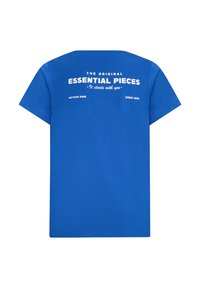 T-shirt in cotone blu con collo a giro e maniche corte. Sul retro è presente un testo bianco: "I PEZZI ESSENZIALI ORIGINALI - Inizia con te - RETOUR DN" con l'anno "DAL 1989."