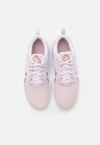 Zapatillas de deporte rosa claro con parte superior de malla, cordones blancos y detalles en cobre. Punta redondeada y tira en el talón para facilitar el uso.