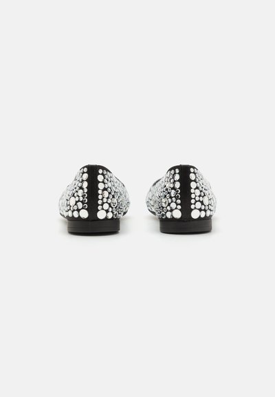 Zapatos negros planos adornados con tachuelas de diferentes tamaños en blanco y plata. Punta redondeada, textura suave y diseño minimalista.