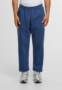 Blauwe sweats met een elastische tailleband en zijzakken, gemaakt van zachte stof, gecombineerd met grijze en witte sportschoenen.